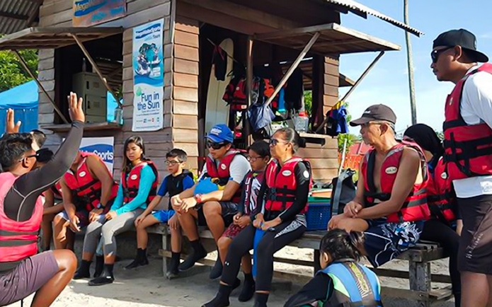 Group receiving safety briefing for jet ski experience in Langkawi, wearing life jackets.