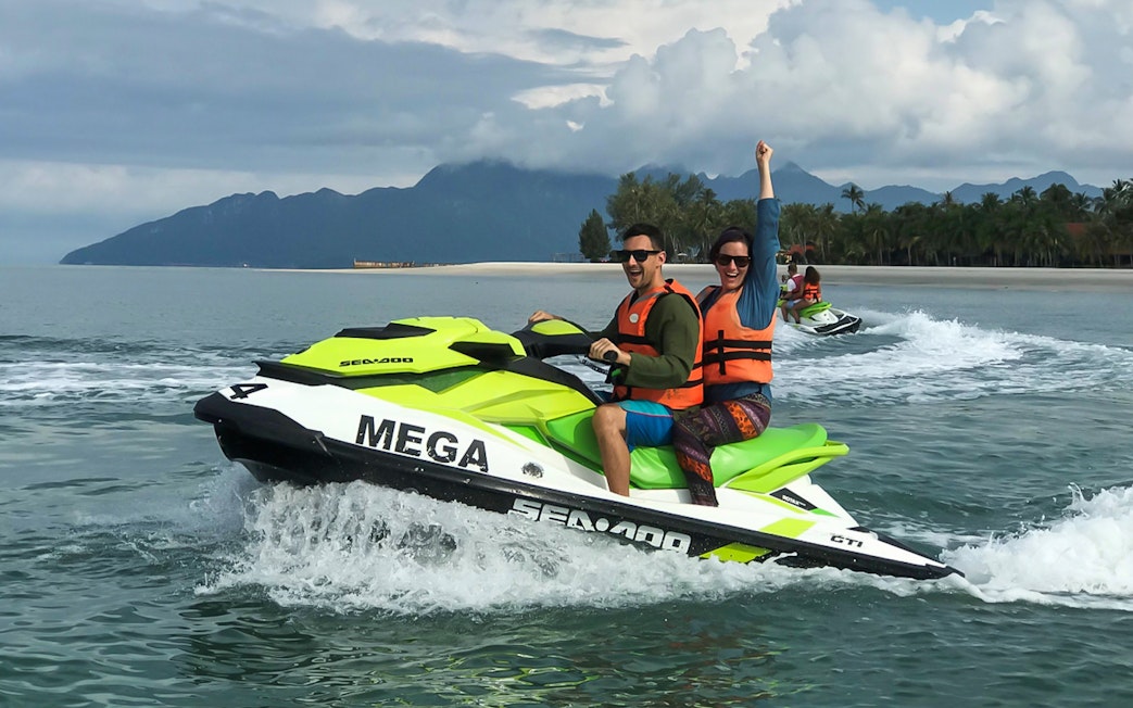 Jet skiing on Langkawi waters with lush mountains in the background.