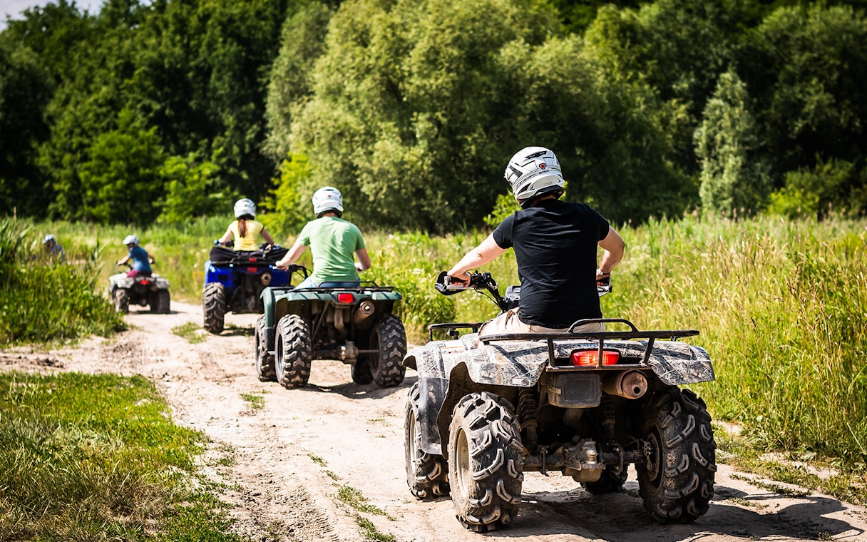 ATV riders on a dirt trail through lush greenery in Langkawi.