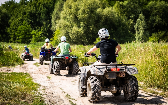 ATV riders on a dirt trail through lush greenery in Langkawi.