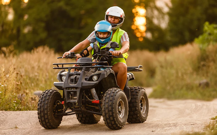 Two people riding an ATV on a dirt path during a Langkawi adventure tour.