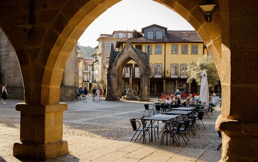 Historic square in Guimarães with medieval architecture and outdoor café tables.
