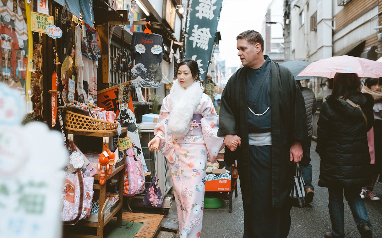 Couple in traditional kimonos walking through a Kyoto market.