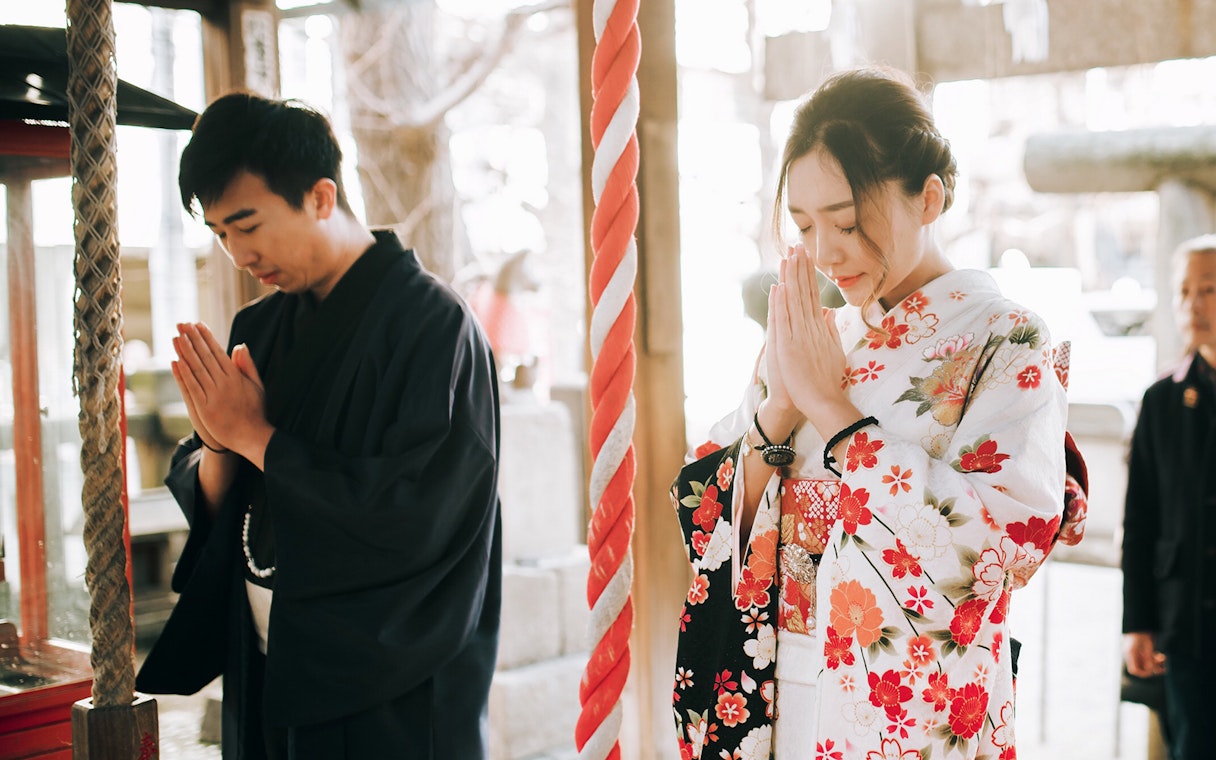 People in traditional kimonos praying at a shrine in Kyoto.