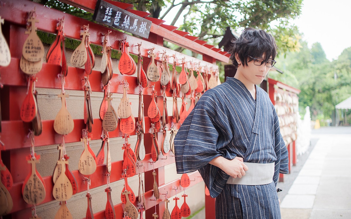 Person in kimono near ema plaques at a Kyoto shrine.