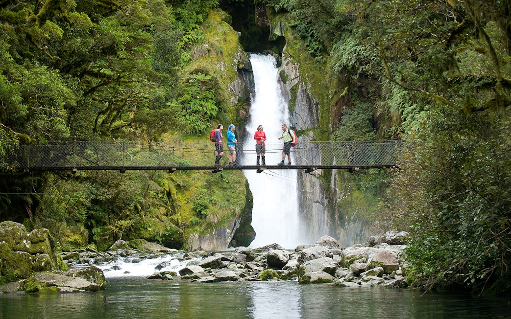 Group on bridge with waterfall view during Giant Gate Falls walking tour.