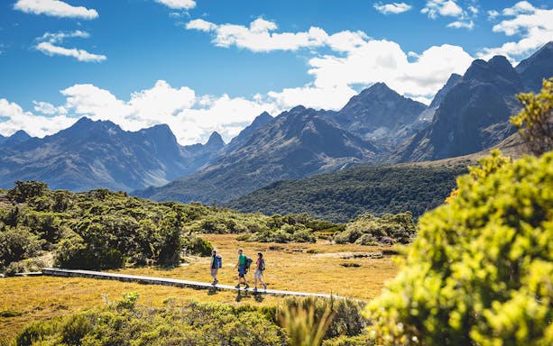 Hikers on Routeburn Track with mountains in Fiordland National Park, New Zealand.