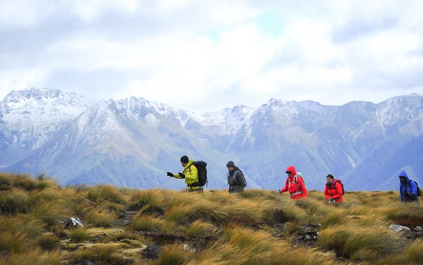Hikers on Kepler Track with snow-capped mountains in Te Anau, New Zealand.