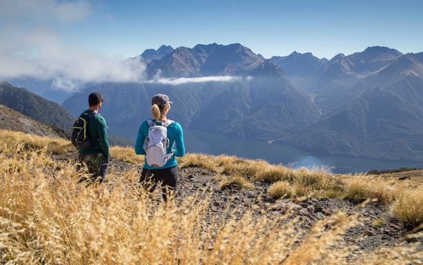 Hikers overlooking mountains and lake on Kepler Track, Te Anau.