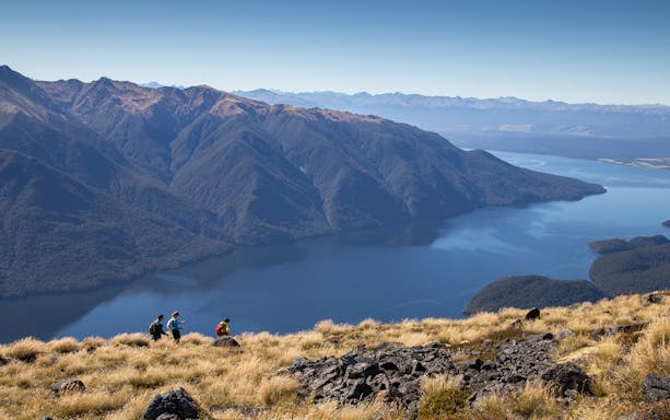 Hikers on Kepler Track with Lake Te Anau and mountains in the background, New Zealand.