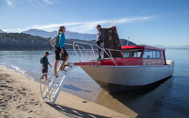 Travelers boarding Kepler Water Taxi for guided heli hike to Kepler Track from Te Anau.
