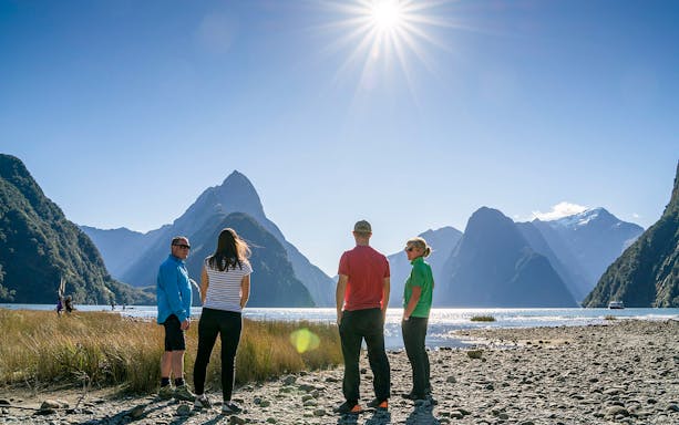 Group hiking near Lake Marian with mountain views in New Zealand.