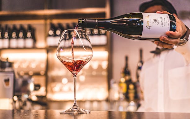 Pouring red wine at a winery in Arrowtown during a guided tour with Queenstown transfers.