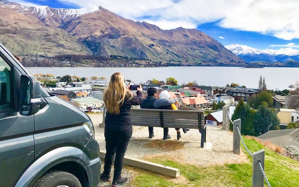 Tourists enjoying a scenic view of Lake Wanaka and mountains in Arrowtown, New Zealand.