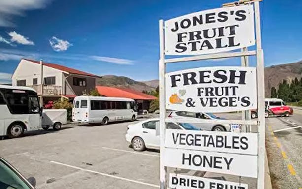 Jones's Fruit Stall sign with buses parked in Arrowtown, New Zealand.