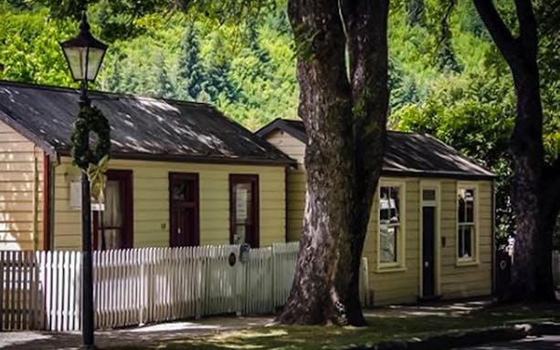 Historic cottages in Arrowtown, New Zealand, surrounded by trees on the Platinum Tour.