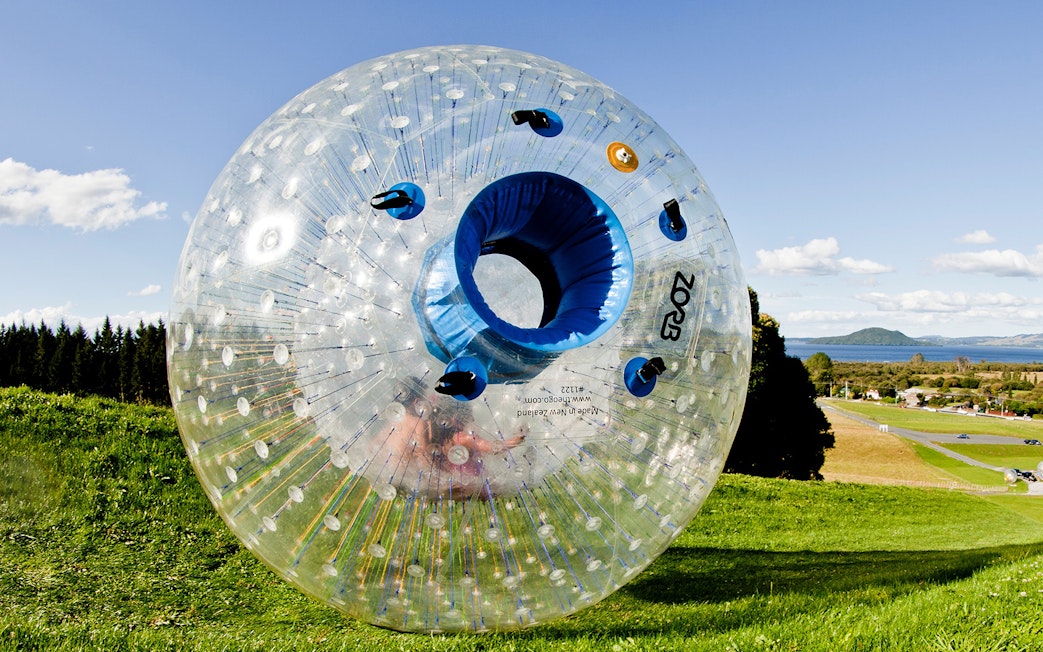 Zorb inflatable ball on a grassy hill with scenic landscape in the background.