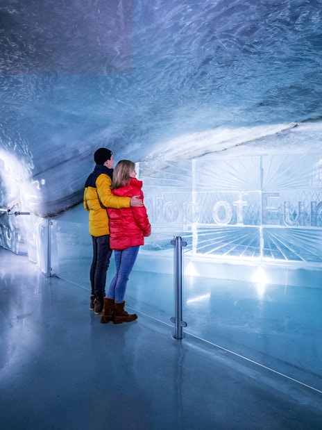 Couple exploring ice tunnel at Jungfraujoch, Switzerland.