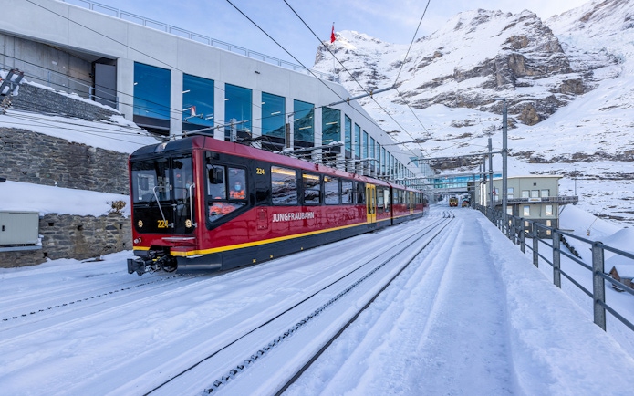 Jungfraubahn train arriving at snowy Jungfraujoch station, Switzerland.