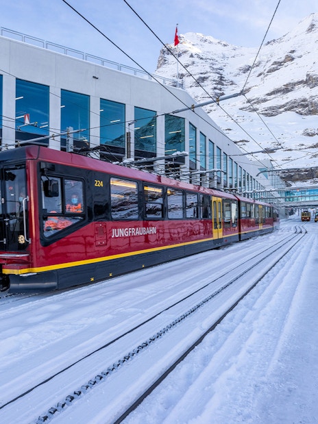 Jungfraubahn train arriving at snowy Jungfraujoch station, Switzerland.