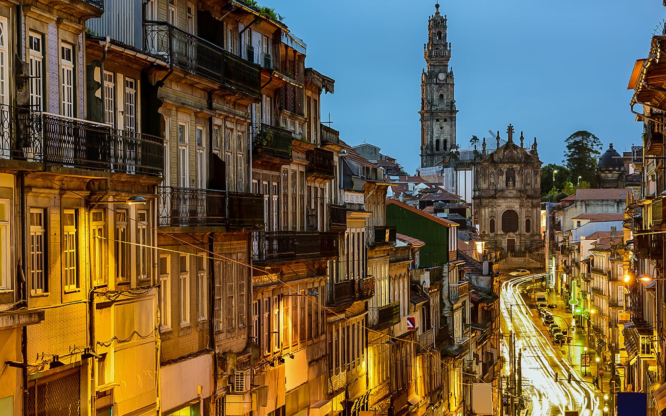 Porto street view at night with Clérigos Tower in the background.