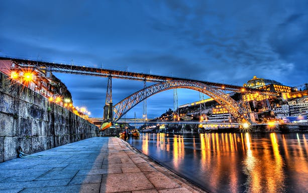 Dom Luís I Bridge illuminated at night over the Douro River in Porto, Portugal.