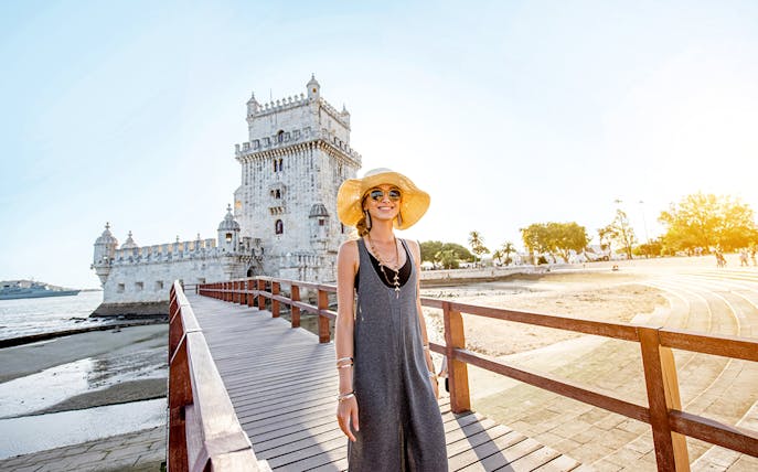 Woman standing on a boardwalk near Belém Tower in Lisbon during a guided tour.
