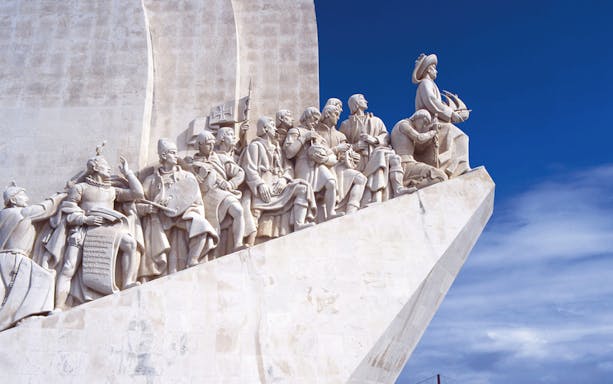 Monument of Discoveries in Lisbon with explorers' statues under a blue sky.