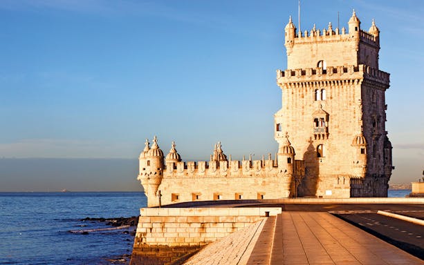 Belém Tower by the Tagus River on a sunny day in Lisbon.