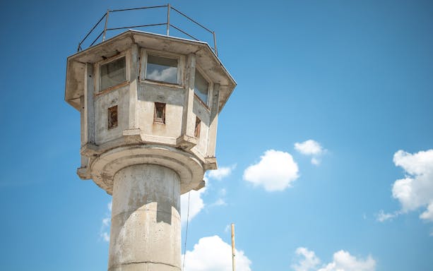 Watchtower from the Cold War era in Berlin against a blue sky.