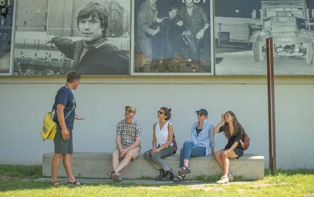 Tour guide explaining Cold War history to a group in front of Berlin Wall photos.