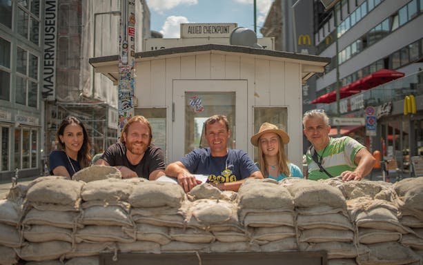 Tourists at Checkpoint Charlie in Berlin during a Cold War guided tour.
