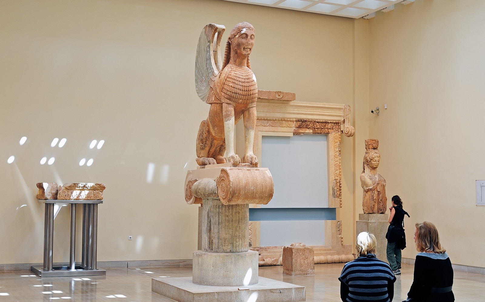 Visitors observing ancient sculptures at Delphi Archaeological Museum.