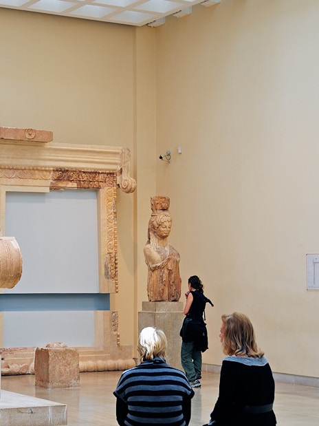 Visitors observing ancient sculptures at Delphi Archaeological Museum.
