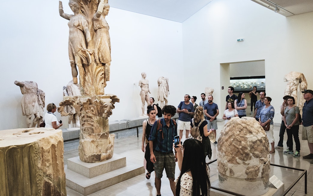 Visitors viewing ancient sculptures at Delphi Archaeological Museum.