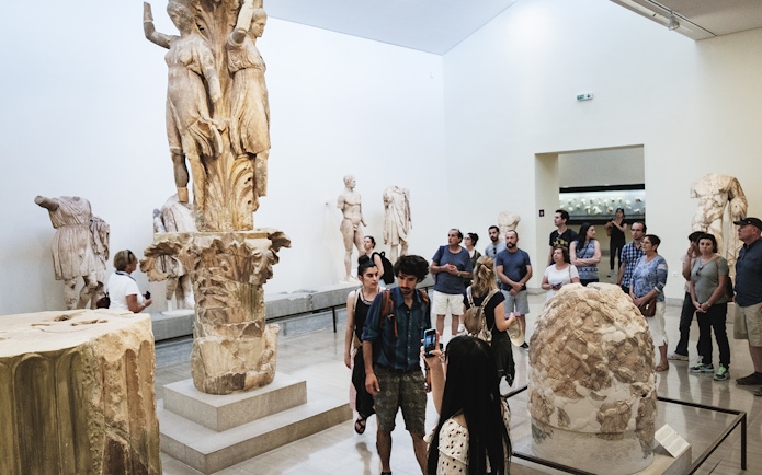 Visitors viewing ancient sculptures at Delphi Archaeological Museum.
