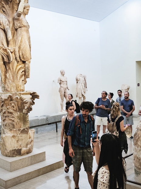 Visitors viewing ancient sculptures at Delphi Archaeological Museum.
