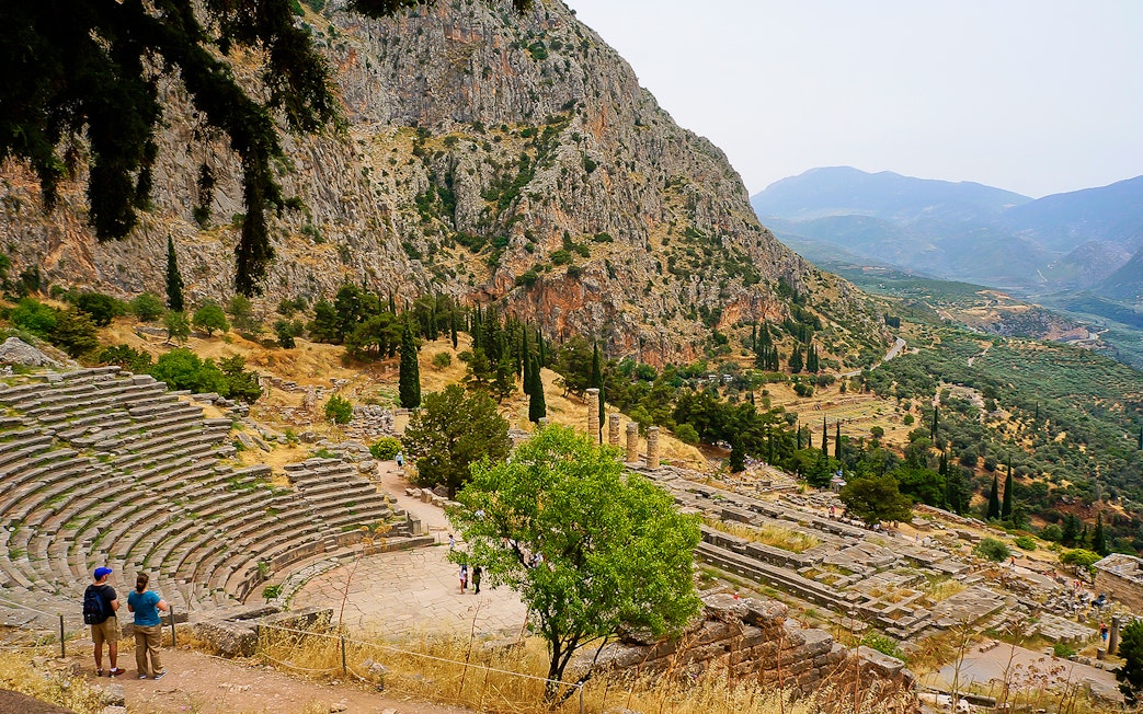 Visitors at the Ancient Theater of Delphi with mountainous landscape in Greece.