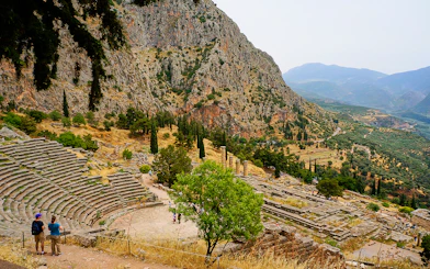 Visitors at the Ancient Theater of Delphi with mountainous landscape in Greece.