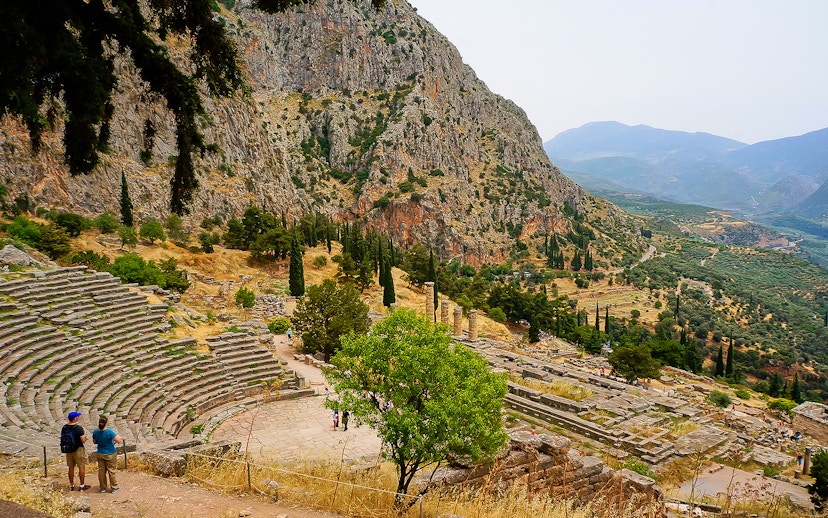 Visitors at the Ancient Theater of Delphi with mountainous landscape in Greece.