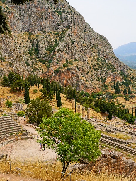 Visitors at the Ancient Theater of Delphi with mountainous landscape in Greece.