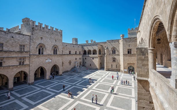 Courtyard of the Palace of the Grand Master of the Knights of Rhodes with visitors exploring.