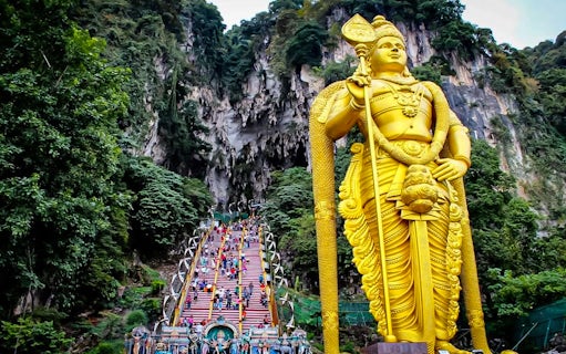 Batu Caves entrance with golden statue and colorful steps, Kuala Lumpur tour.