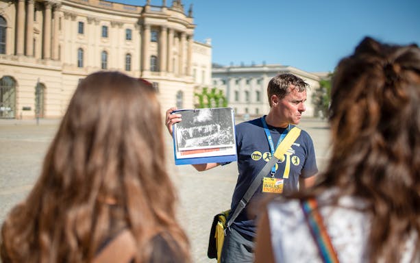 Tour guide showing historical photo during Berlin tour.