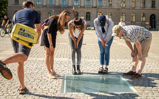 Visitors observing the Bebelplatz memorial during a 3-hour guided tour of Berlin.