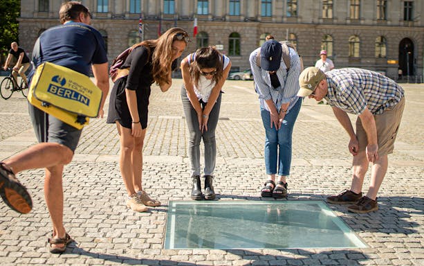 Visitors observing the Bebelplatz memorial during a 3-hour guided tour of Berlin.