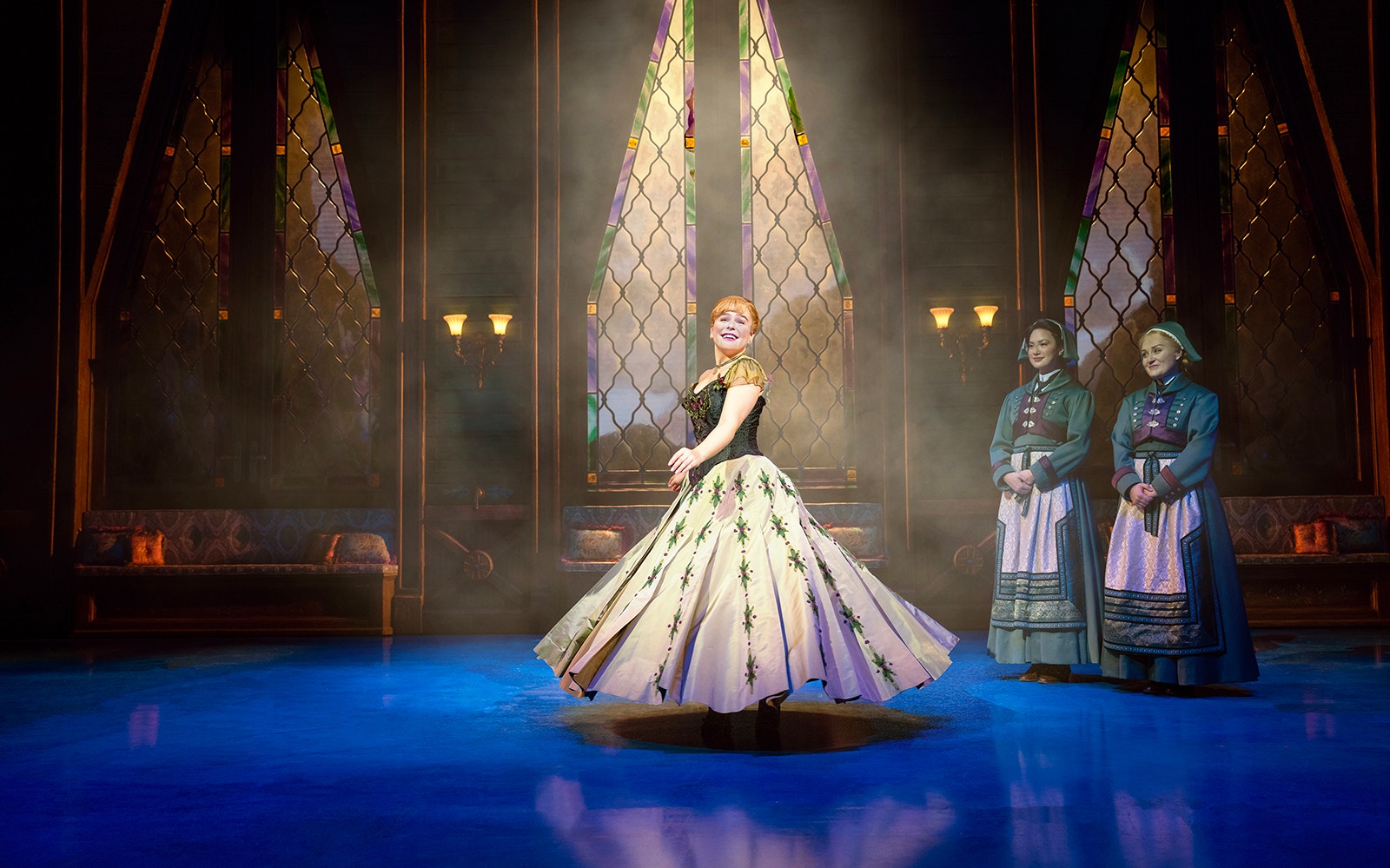 Performer twirling on stage during Frozen The Musical with stained glass backdrop.