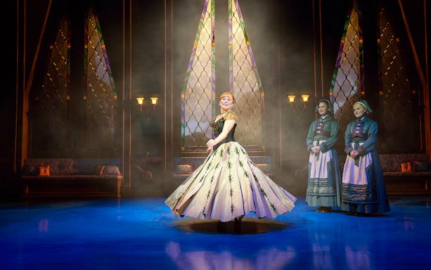 Performer twirling on stage during Frozen The Musical with stained glass backdrop.