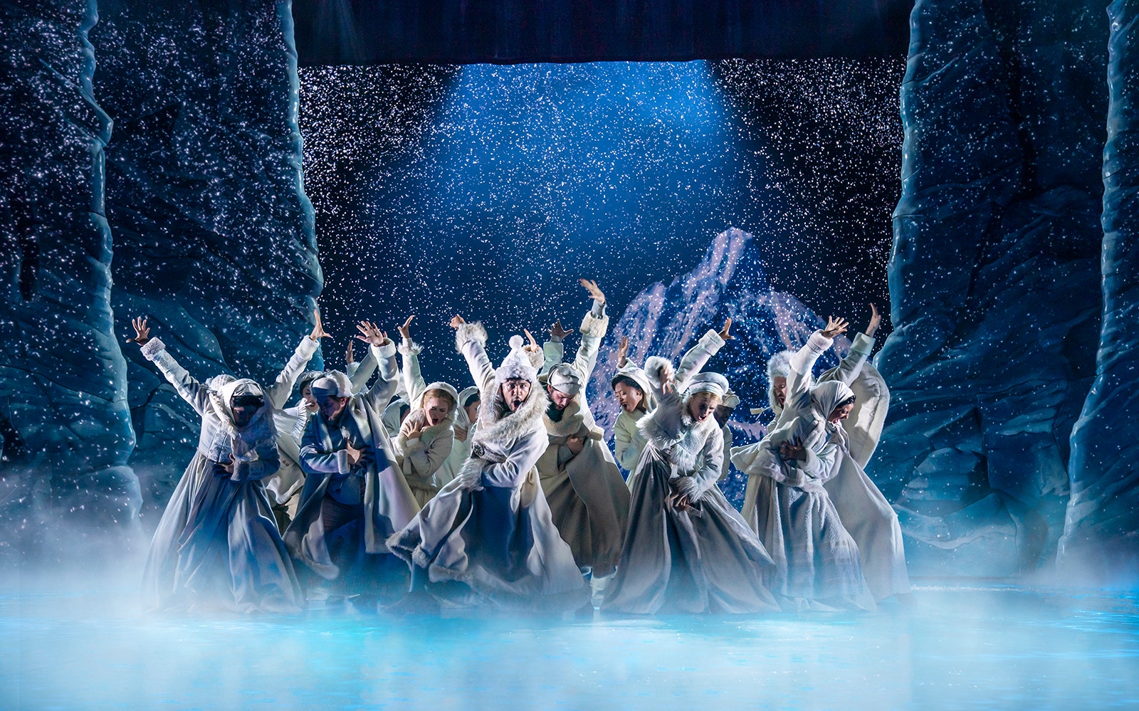 Performers in winter costumes dancing on stage in Frozen The Musical.