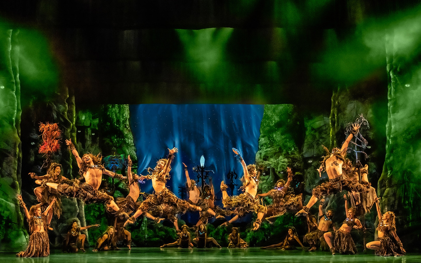 Performers in tribal costumes dancing energetically on stage during Frozen The Musical.
